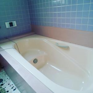 志布志市みのる民泊2号的浴室铺有蓝色瓷砖,配有白色浴缸。