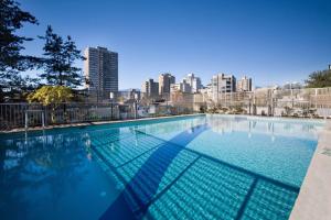 温哥华戴维桑德曼套房酒店的一座大型游泳池,其背景是城市天际线
