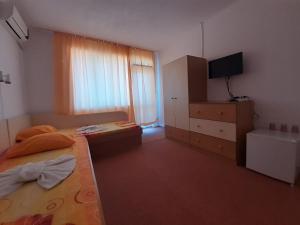普里莫尔斯科Guest House Malkata Stopanka的一间卧室配有一张床、梳妆台和电视。