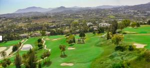 马贝拉Apartamento Marbella的享有高尔夫球场的空中景色,以山脉为背景