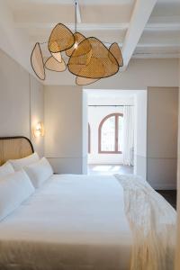 TorrojaORA Hotel Priorat, a Member of Design Hotels的卧室配有白色的床和2盏吊灯。
