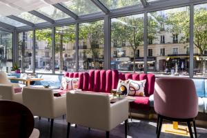 巴黎Hôtel Nude Paris - Color Vision的餐厅设有粉红色的椅子和桌子以及窗户。