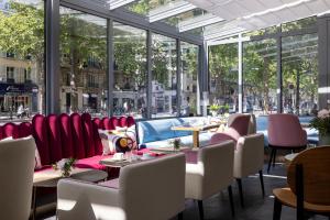 巴黎Hôtel Nude Paris - Color Vision的餐厅设有红色的椅子和桌子以及窗户。