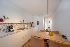 阿尔斯特Georges & Madeleine Apartments的厨房配有白色橱柜和木桌