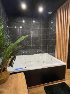 贝济耶Suite cocooning & spa的浴室设有浴缸,铺有黑色瓷砖。