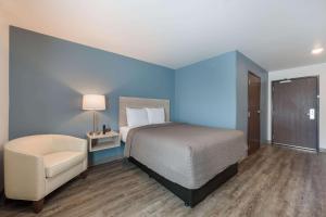 康科德WoodSpring Suites Concord-Charlotte Speedway的蓝色卧室,配有床和椅子