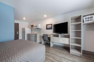康科德WoodSpring Suites Concord-Charlotte Speedway的一间卧室配有一张床和一张书桌及电视