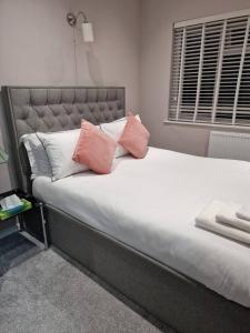格雷夫森德Beautiful and modern House in Gravesend的床上配有粉色和白色枕头的床