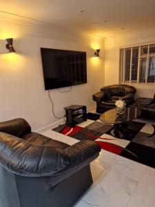 格雷夫森德Beautiful and modern House in Gravesend的客厅配有皮革家具和平面电视