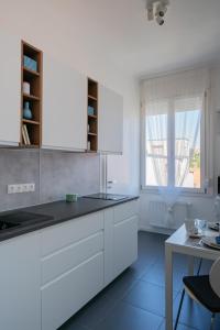 布达佩斯Sunhill Studio的厨房配有白色橱柜、桌子和窗户。