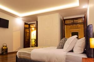 基多Suites Experience by Hotel David的一间卧室配有一张带白色床单的床和电视。