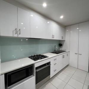 墨尔本Carlton Stunning View Apartment 150m away from University of Melbourne的厨房配有白色橱柜和炉灶烤箱。