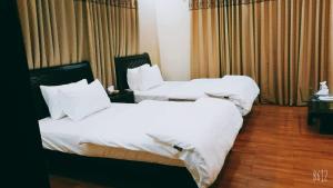 卡拉奇The Elet Business Hotel的配有白色床单的酒店客房内的两张床