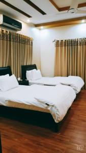 卡拉奇The Elet Business Hotel的配有窗帘的酒店客房内的两张床