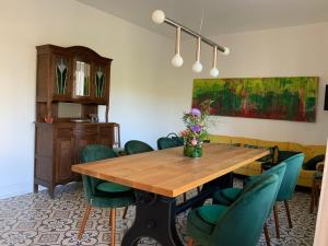 布雷姆Ferienhaus Mosel 2.0的一间带木桌和绿色椅子的用餐室