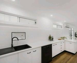 Chittaway PointLakeview House LILAC的厨房配有白色橱柜和黑色水槽