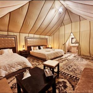 梅尔祖卡Desert Lover's Luxury Camp的一间卧室配有两张床,帐篷内配有一张桌子