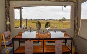 Okavango DeltaAmber River Camp的一间带两个盥洗盆和窗户的浴室