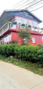 Xuân TrườngMr.Khanh Coffee的前面有灌木丛的红色建筑