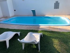 考卡亚Diversão, férias, casa na praia de cumbuco.的一个带两把白色椅子的游泳池