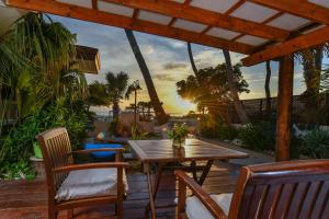 棕榈滩阿鲁巴日落海滩一室公寓酒店的甲板上的木桌和椅子,享有日落美景