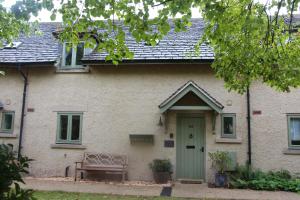 萨默福德凯恩斯Coot Cottage的绿色门和长凳的房子