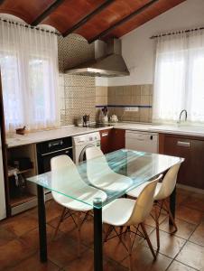 GójarCasa de Campo Los Manueles Ideal Perros Pet Friendly的厨房配有玻璃桌和白色椅子