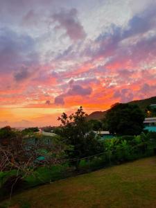 LaborieJuju's Cottage with magnificent views的落日,在有栅栏和树木的田野上