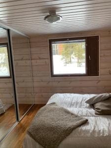 库萨莫VillaRiutta Ruka的一间卧室设有木墙和一张带窗户的床