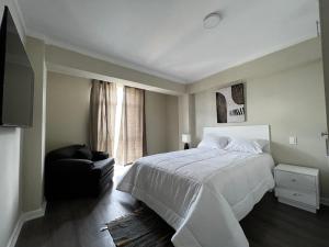 CarazDepartamentos Caraz的卧室配有白色的床和黑椅