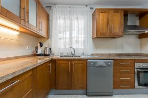 阿罗纳Los Cristianos Duplex的厨房配有木制橱柜、水槽和洗碗机。