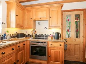 霍利韦尔Ash Farm Cottage的厨房配有木制橱柜和炉灶。