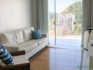 瓜鲁雅Apartamento da Pitangueiras的客厅配有白色沙发和大窗户