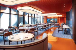 澳门新濠天地 -摩珀斯的餐厅设有桌椅和大窗户。