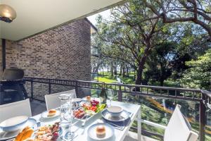 尼尔森湾Bay Parklands, 29 2 Gowrie Avenue - views, air conditioning, Wi-Fi, Pool, tennis court and spa的阳台上的白色桌子和食物