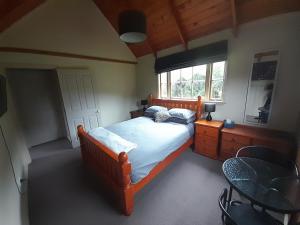 新普利茅斯Georges BnB Nature and Lifestyle Retreat的一间卧室配有一张床、一张桌子和一个窗户。