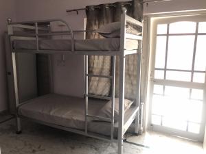 德拉敦Welcome Hostel的带窗户的客房内的两张双层床