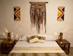 麦德林Refugio del Jaguar的一间卧室配有一张带两张桌子的床,墙上挂有绘画作品