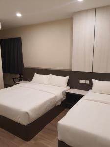 怡保T SQUARE HOTEL (IPOH)的配有白色床单的酒店客房内的两张床