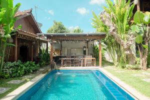 金巴兰RedDoorz at Villa Krisna Balangan Beach的一座带桌子的房屋后院的游泳池