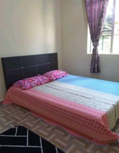 Kampong Alor GajahNor Su Homestay的一张带粉色毯子和窗户的床