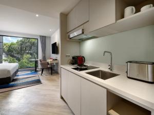 曼谷曼谷素坤逸奥克伍德华庭工作室酒店的一个带水槽的厨房和一张位于客房内的床