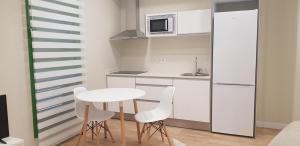 阿尔巴塞特Apartamentos Ilustración的一间带桌子和白色椅子的小厨房