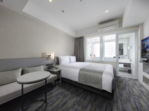 东京Villa Fontaine Grand Haneda Airport的酒店客房,配有床和沙发