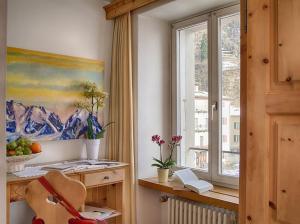 波斯基亚沃Poschiavo Suisse Hotel的客房设有窗户、绘画和椅子