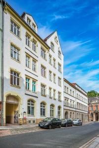 梅森cozy Apartment SOLARIS in Meißen Altstadt Netflix的一座白色的大建筑,前面有汽车停放