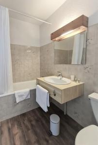 穆捷终点三村酒店的一间带水槽、浴缸和镜子的浴室
