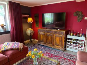MalsfeldHappy Teapot Apartment的一间客厅,在红色的墙上配有电视