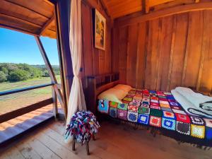 TurvoPousada Ninho da Gralha的木制客房的一张床位,设有窗户
