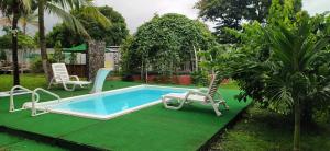 查梅Dharma Casa Holistica, Vivero, Yoga y Retiros的庭院内的游泳池,配有两把椅子和一张桌子